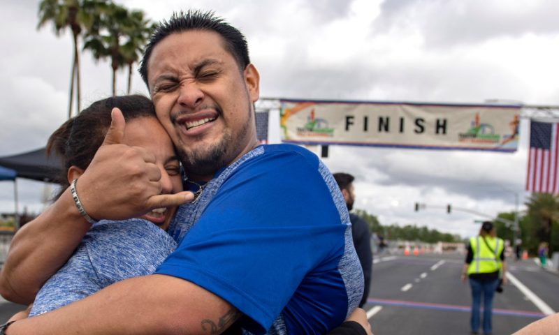 Fernando Escobar is overcome with emotion after finishing his first half marathon in Tustin on Sunday, March 3, 2019. Nine months ago Escobar was living under a bridge in Redlands, addicted to methamphetamine and alcohol. "I feel like I defeated a monster," he said of finishing the race. He hugs Angelina Cabrera. Both are living at the OC Rescue Mission's Village of Hope. (Photo by Mindy Schauer, Orange County Register/SCNG)